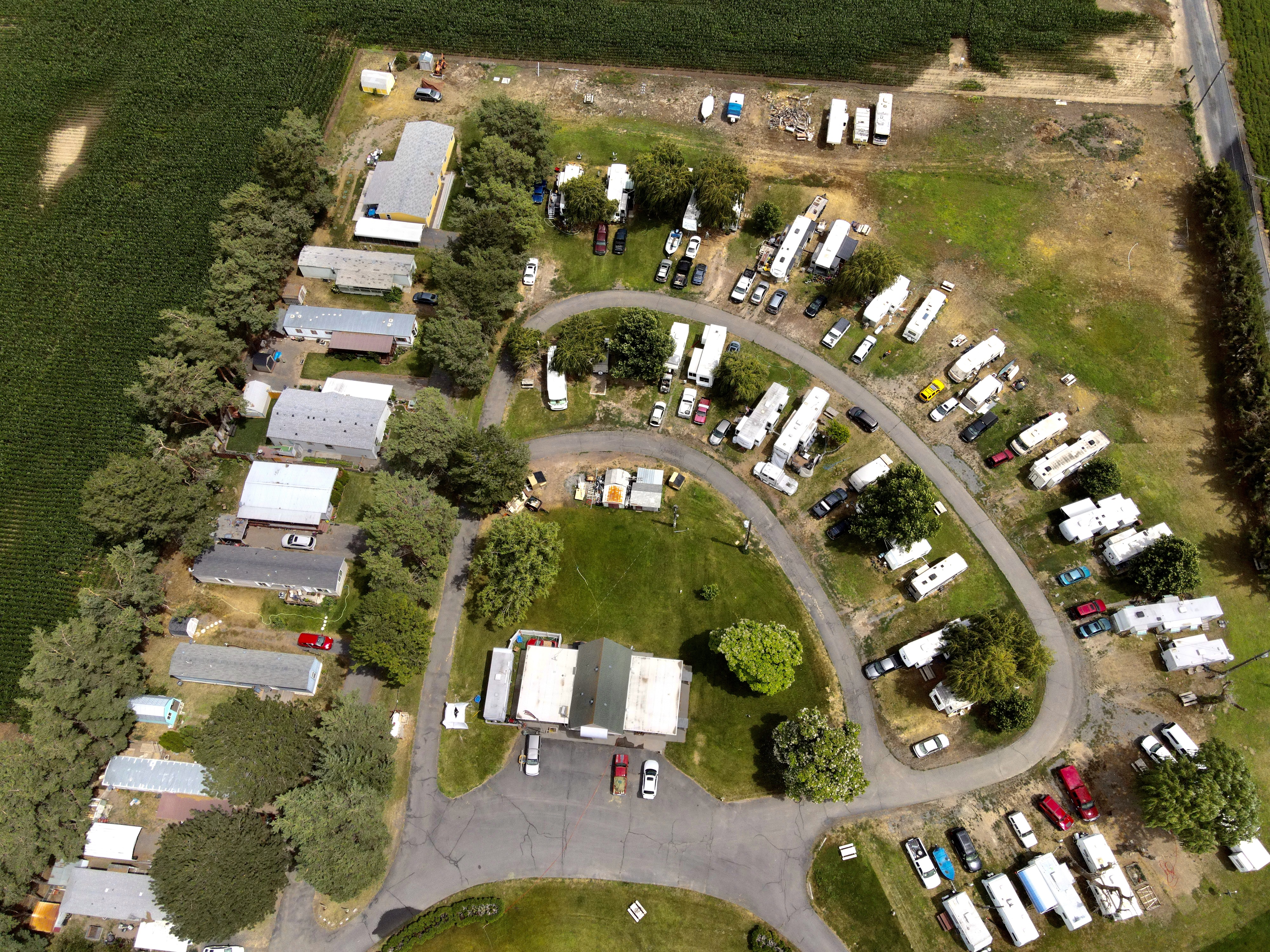 High-angle aerial of long-term RV sites around the loop road at Willows Trailer Village with farm fields beyond